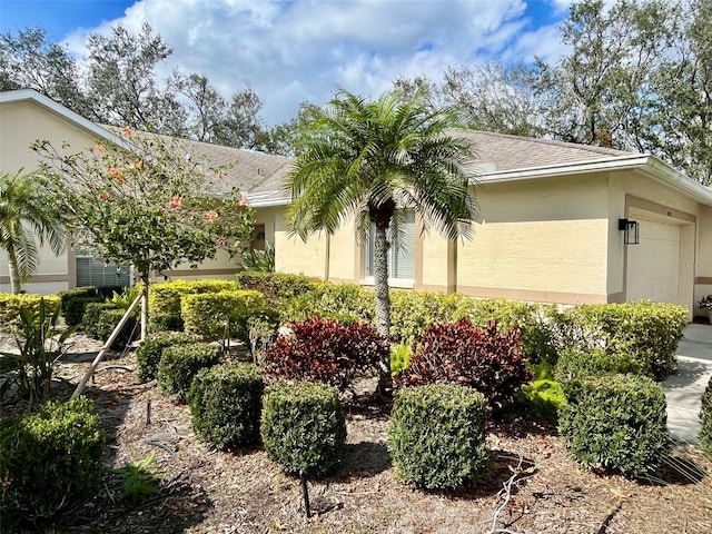 view of front facade with a garage, a shingled roof, and stucco siding