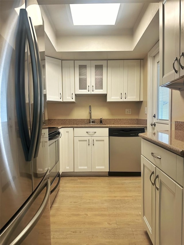 kitchen with white cabinetry, light wood-style floors, appliances with stainless steel finishes, and a sink