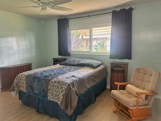 bedroom featuring a textured ceiling, a ceiling fan, and wood finished floors