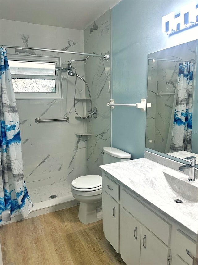 bathroom featuring vanity, a stall shower, wood finished floors, and toilet