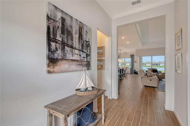 hallway with ornamental molding, wood finish floors, visible vents, and baseboards