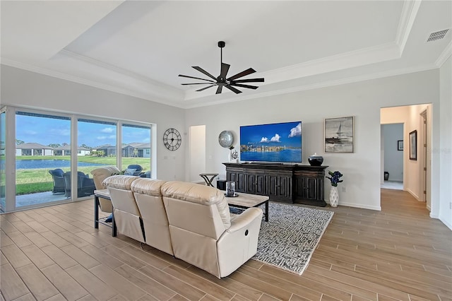 living area featuring visible vents, a raised ceiling, ceiling fan, ornamental molding, and wood finish floors