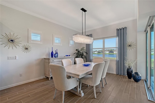 dining space featuring a water view, baseboards, crown molding, and wood finish floors