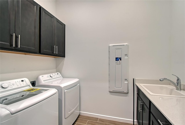 laundry area featuring cabinet space, electric panel, baseboards, washer and dryer, and a sink