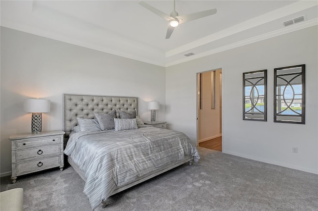 bedroom with dark colored carpet, a tray ceiling, visible vents, and a ceiling fan