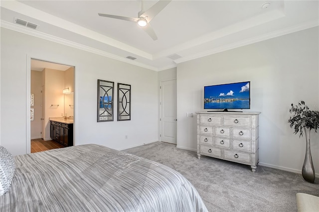 bedroom with a tray ceiling, visible vents, light carpet, and baseboards