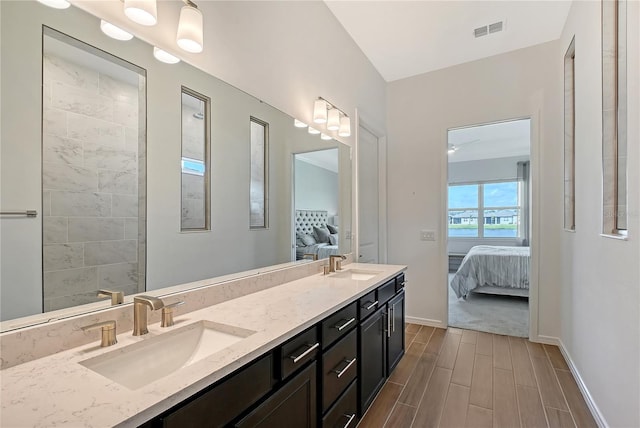 ensuite bathroom with a sink, double vanity, connected bathroom, and wood tiled floor