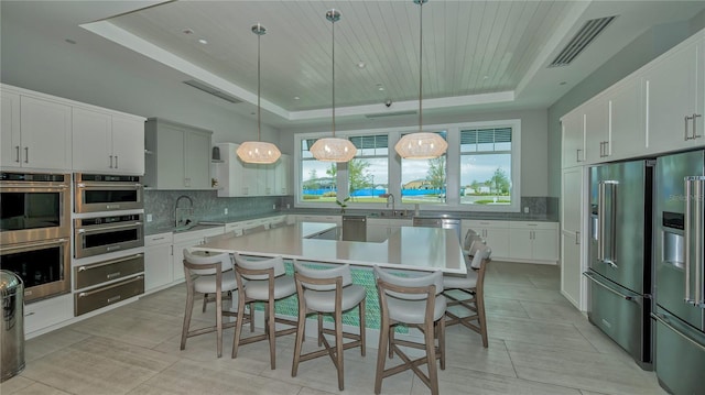 kitchen featuring a raised ceiling, light countertops, a kitchen island, and hanging light fixtures