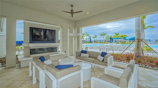 view of patio / terrace with a water view, an outdoor living space with a fireplace, a community pool, and ceiling fan