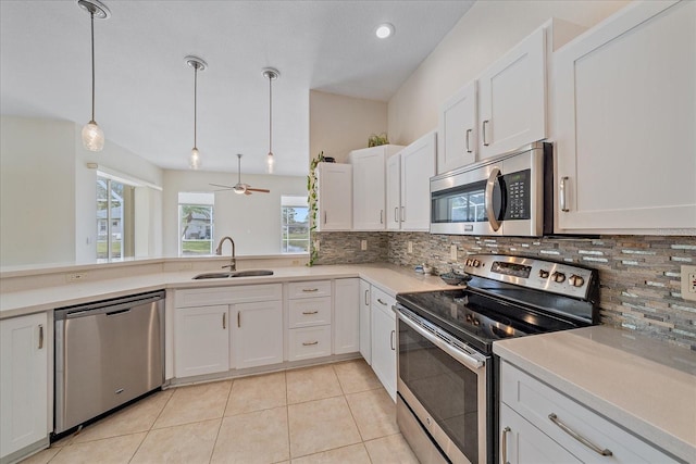 kitchen with decorative light fixtures, sink, stainless steel appliances, and white cabinets