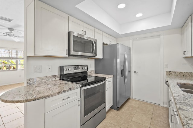 kitchen featuring appliances with stainless steel finishes, a raised ceiling, and white cabinets