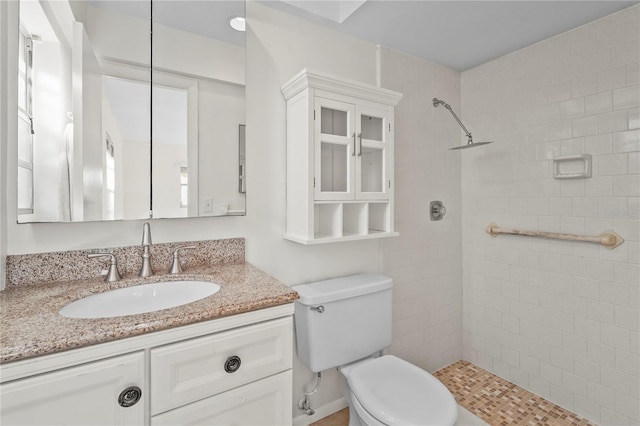 full bath featuring a tile shower, vanity, and toilet