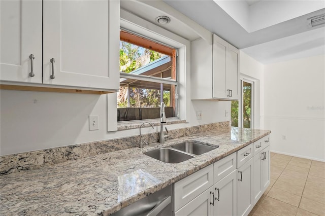 kitchen featuring visible vents, white cabinets, light stone counters, a sink, and light tile patterned flooring