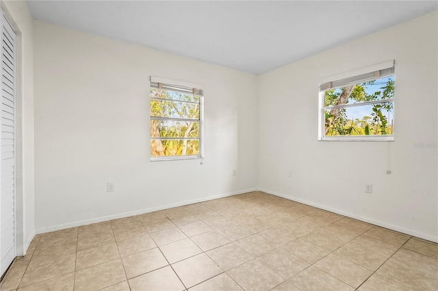 unfurnished room featuring light tile patterned floors, baseboards, and a wealth of natural light