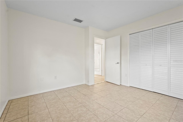 unfurnished bedroom featuring light tile patterned floors, a closet, visible vents, and baseboards