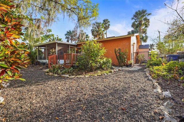 rear view of house with fence, a sunroom, and stucco siding