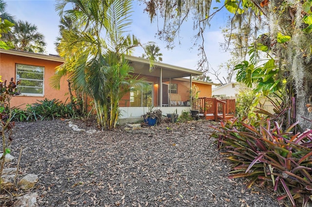 back of house featuring a sunroom and stucco siding