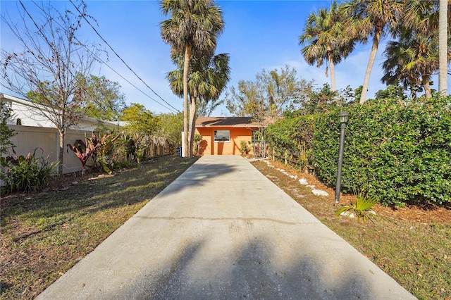 view of front of property featuring stucco siding, driveway, and fence