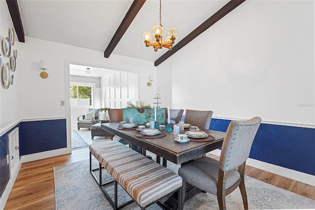 dining room with lofted ceiling with beams, an inviting chandelier, baseboards, and wood finished floors