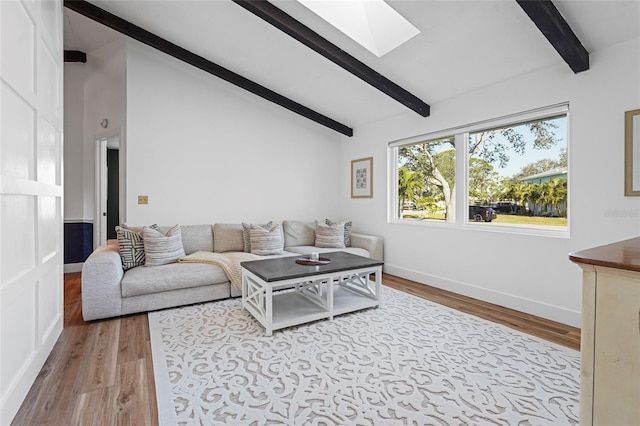 living area featuring lofted ceiling with skylight, baseboards, and wood finished floors