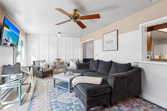 tiled living room with ceiling fan and a textured ceiling