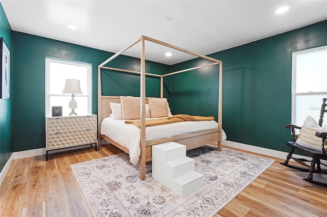 bedroom with multiple windows, wood finished floors, and baseboards