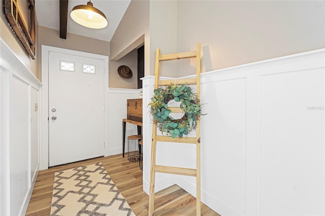 foyer with light wood-type flooring, wainscoting, and a decorative wall