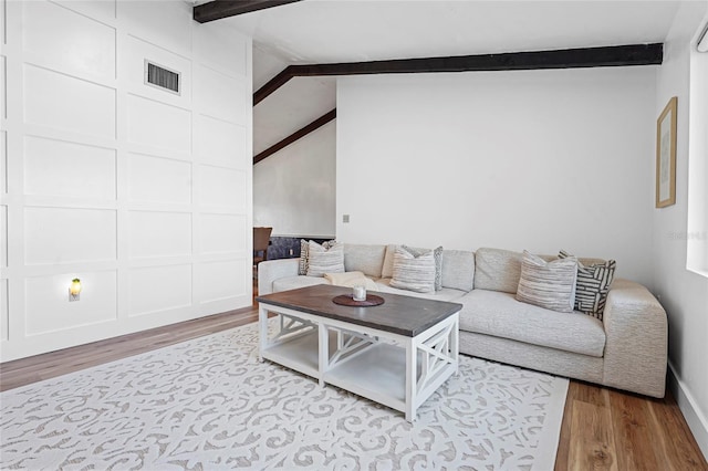 living area featuring lofted ceiling with beams, wood finished floors, and visible vents