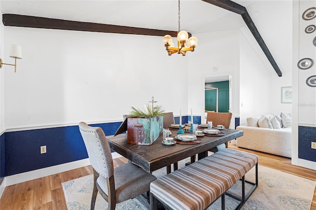 dining room featuring vaulted ceiling with beams, an inviting chandelier, baseboards, and wood finished floors