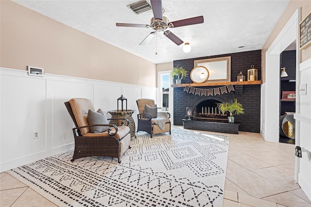 sitting room featuring tile patterned flooring, a ceiling fan, a decorative wall, and a textured ceiling