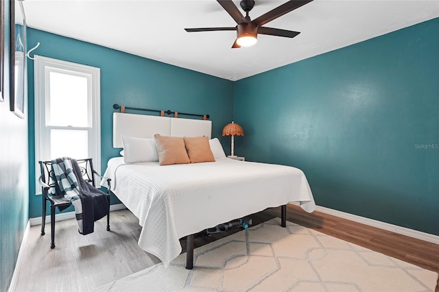 bedroom with a ceiling fan, baseboards, and wood finished floors