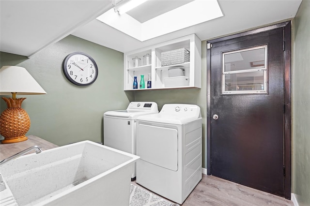 laundry area featuring laundry area, a sink, light wood-style flooring, and washing machine and clothes dryer