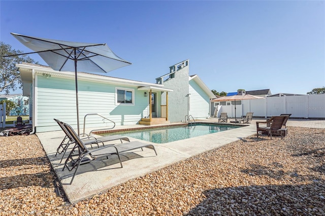 rear view of house with a patio, fence, and a fenced in pool