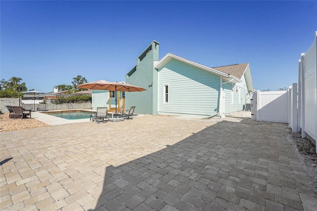 back of house featuring a patio area, a fenced backyard, a gate, and a fenced in pool