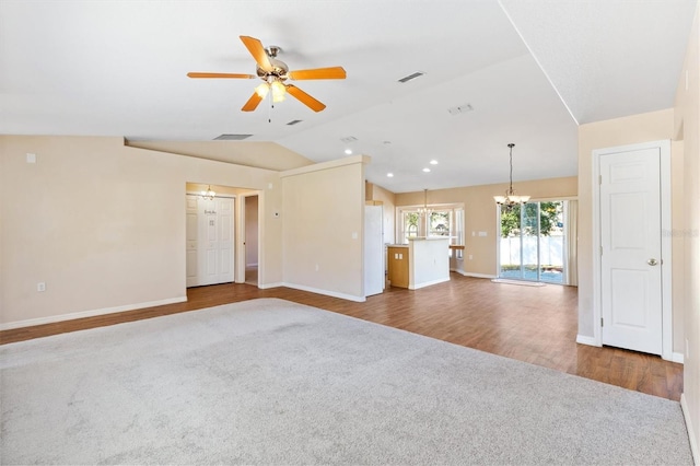 unfurnished living room with visible vents, vaulted ceiling, wood finished floors, and ceiling fan with notable chandelier