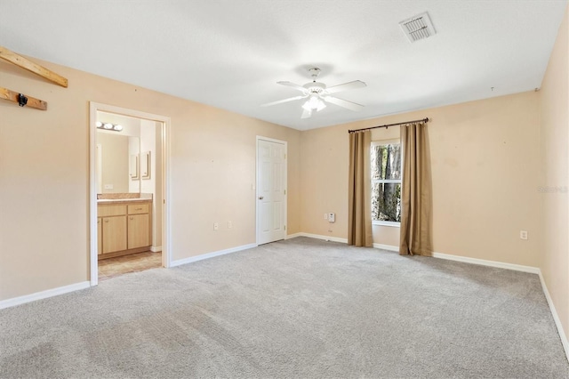 unfurnished bedroom with baseboards, ensuite bathroom, visible vents, and light colored carpet