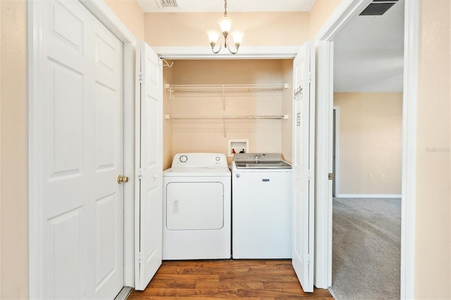 laundry room featuring dark wood-style flooring, visible vents, an inviting chandelier, washing machine and dryer, and laundry area