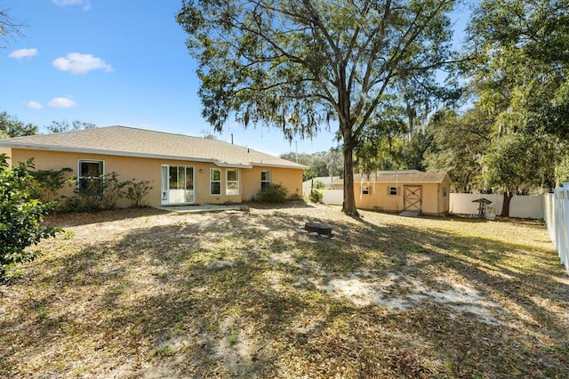 back of property featuring stucco siding, a fenced backyard, an outdoor structure, and a storage unit