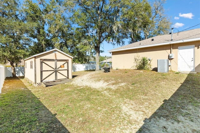 view of yard featuring an outbuilding, central AC, a fenced backyard, and a shed