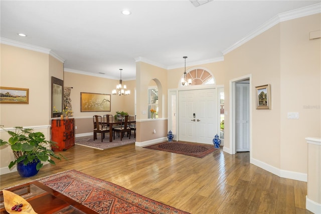 foyer entrance featuring hardwood / wood-style floors, crown molding, a notable chandelier, and baseboards