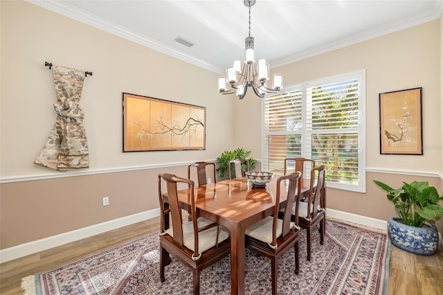 dining area with visible vents, wood finished floors, an inviting chandelier, and ornamental molding