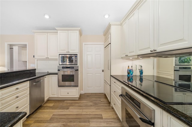 kitchen featuring under cabinet range hood, light wood-style flooring, recessed lighting, and appliances with stainless steel finishes