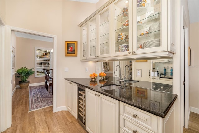 bar featuring a sink, indoor wet bar, light wood-style floors, and beverage cooler