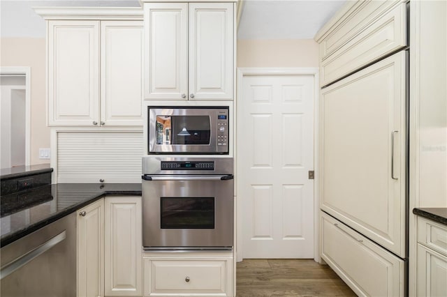 kitchen with dark stone countertops, light wood finished floors, and stainless steel appliances