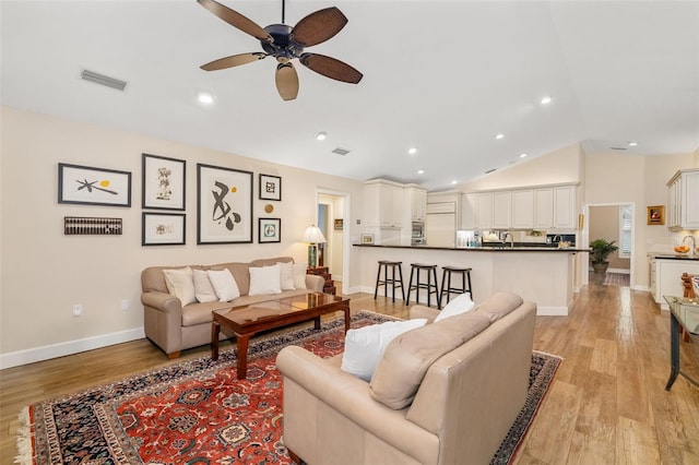 living room with lofted ceiling, baseboards, visible vents, and light wood-type flooring