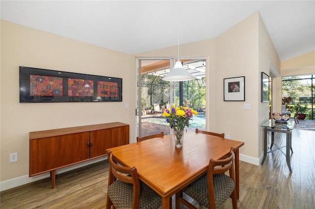 dining space featuring baseboards, lofted ceiling, and wood finished floors