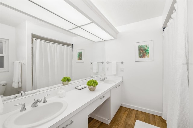 full bathroom with a sink, baseboards, wood finished floors, and double vanity