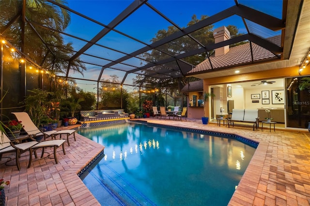 outdoor pool with glass enclosure, a ceiling fan, and a patio area