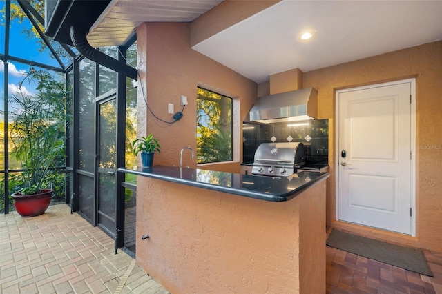 kitchen with brick floor, wall chimney exhaust hood, recessed lighting, and a sink