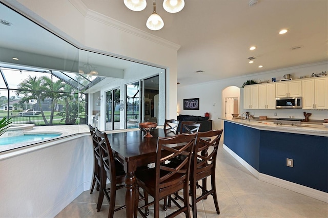 dining space with arched walkways, light tile patterned flooring, crown molding, and recessed lighting